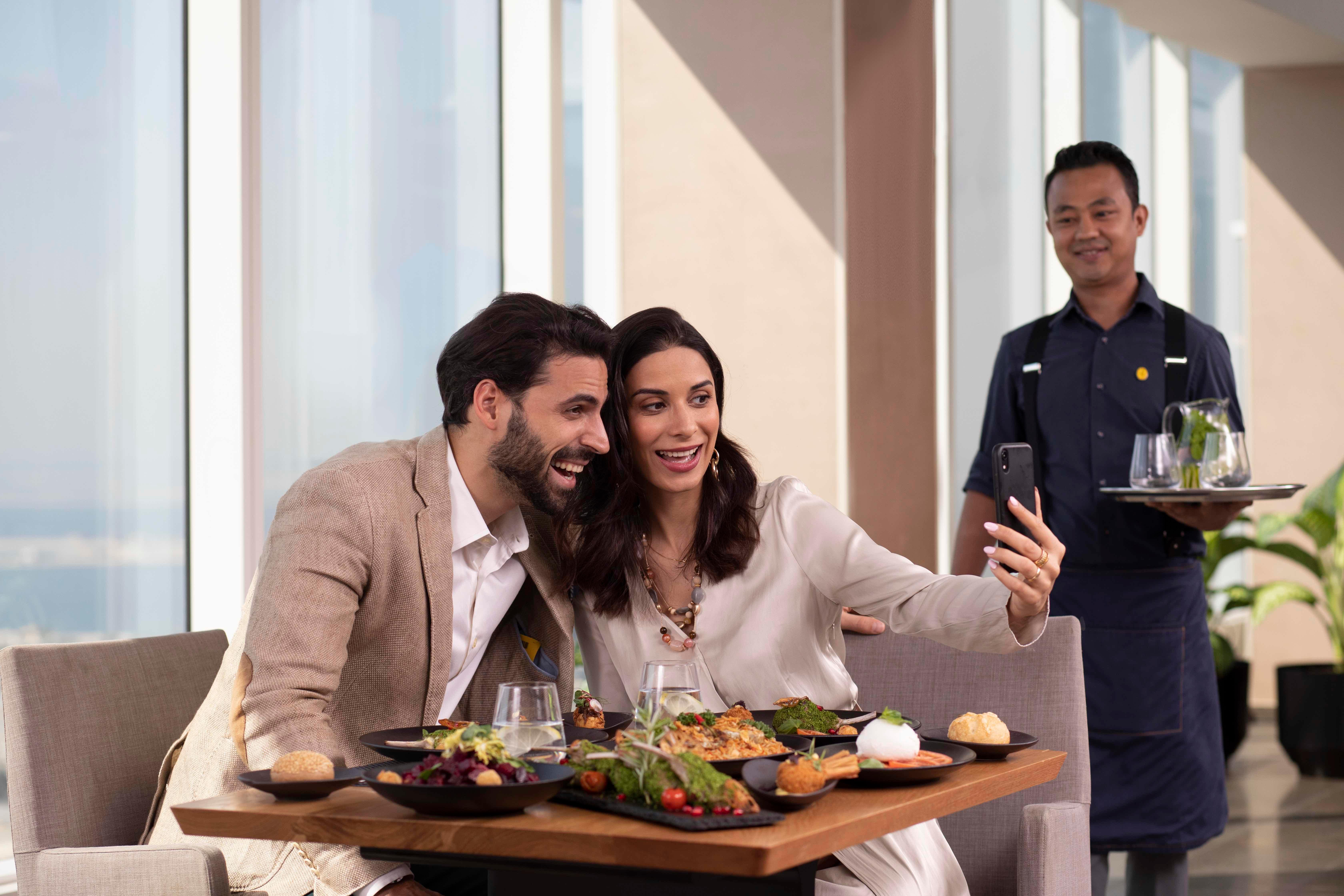 Voco Dubai By Ihg Hotel Bagian luar foto A waiter serving a couple